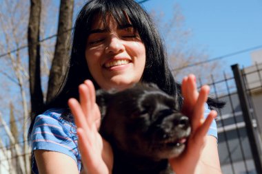 Venezuelalı genç bir Latin kadının portresi, Buenos Aires Arjantin 'de gün batımı güneşinin altında köpeğiyle oynarken çok mutlu bir şekilde gülüyor. kopyalama alanı, insanlar ve evcil hayvan kavramı