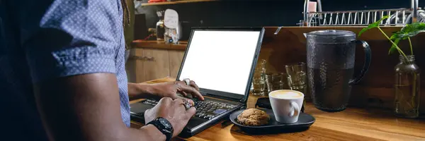 banner of unrecognizable black business man, standing working with his laptop inside restaurant, while having coffee with cookie, freelance business concept, copy space.