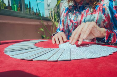 Beyaz Arjantinli kadın tarot okuyucu masada fan şeklindeki güverteden kart alarak terapi amaçlı tarot terapisine başlıyor. Boşluğu kopyala.