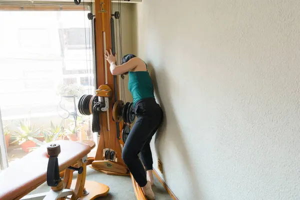 Caucasian adult woman gymnastics and rehabilitation instructor preparing exercise machine, placing weights, leaving it ready to teach class.