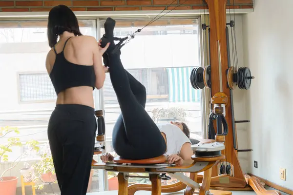两名无法辨认的白人妇女 在家里用滑轮机和重量进行体能训练 锻炼腿和腹部 — 图库照片