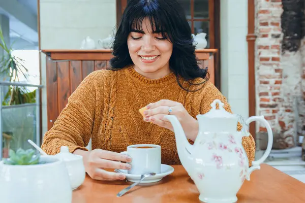 young latin woman enjoying day sitting in coffee shop in afternoon drinking tea, relaxed happy smiling, lifestyles concept