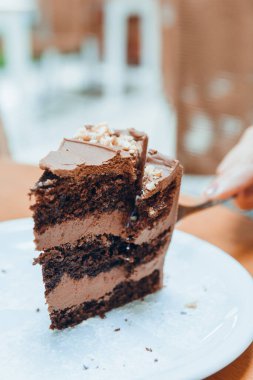 Beyaz porselen tabakta servis edilen beyaz porselen pasta dilimiyle kesilen beyaz beyaz beyaz beyaz beyaz beyaz kadının el resmi, sosyal medya için hamur işi kavramı, kopyalama alanı