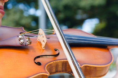 Keman yayının yakın plan çekimi. Açık havada tanınmayan bir kadın tarafından çalınıyor.,