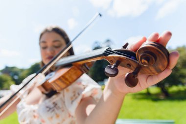 Kemanını akort eden bulanık, beyaz tenli genç kadının geniş açılı yakın çekimi, keman kabuğundaki mandallara odaklan, müzik aletleri konsepti, kopyalama alanı.