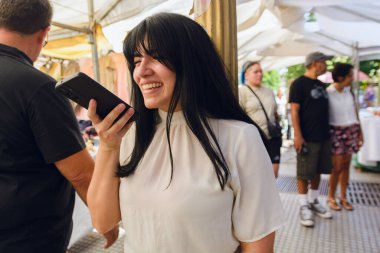 Genç Latin kadın turist mutlu bir şekilde gülümsüyor telefonda sesli mesaj gönderiyor.