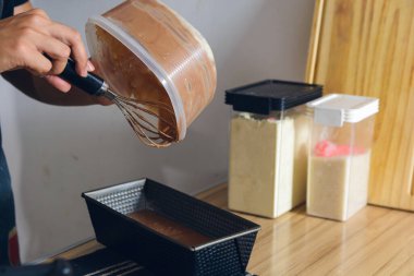 Ev mutfağında el çırpıcısı ile dikilmiş, kek karışımını pişirme tavasına, pasta konseptine, fotokopi alanına dolduran tanınmamış koyu renk saçlı adam..