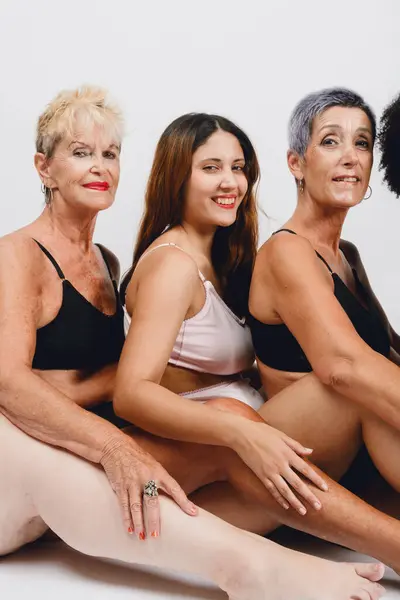 closeup of skin details multiracial and multiethnic female in underwear sitting together in studio with white background.