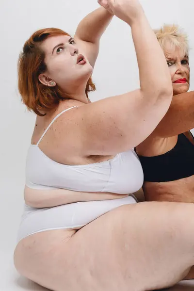 closeup of skin details multiracial and multiethnic female in underwear sitting together in studio with white background.