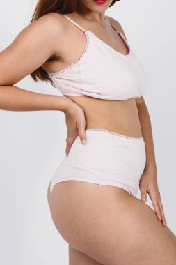 Beyaz iç çamaşırlı bir kadının dikey görüntüsü sosyal ağlar için kadınsı kavramlar, doğal vücutlar ve cilt ve vücut bakımı için poz veriyor..