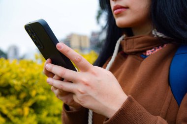 Tanımlanamayan bir kadının el ele tutuştuğu yakın plan fotoğrafı. Park yerinde, kahverengi kıyafetler giyiyor, teknoloji kavramı, fotokopi alanı..