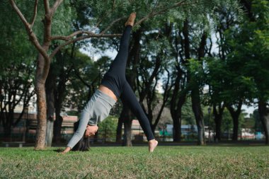 Genç Yoga eğitmeni parkta antrenman yapıyor, asanas yapıyor ve vücudunu esnetiyor, fotokopi alanı, sağlıklı yaşam tarzı konsepti.