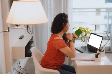 Genç girişimci kadın evde internet pazarlaması öğretiyor, boş ekranlı dizüstü bilgisayarla oturuyor, konuşuyor ve monitöre bakıyor, boşluğu kopyalıyor