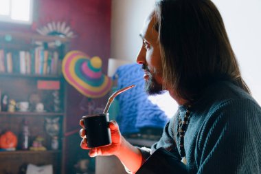 Uzun saçlı ve sakallı Arjantin kökenli genç adamın sabah evde içki arkadaşı, rahat ve düşünceli bir şekilde oturma odasında oturuyor..