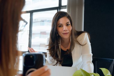 Genç Venezuelalı girişimci kadın ve içerik yaratıcısı, sosyal ağları için telefonda bir video kaydediyor. Dinleyicilerine konuşuyor ve açıklamalar yapıyor..