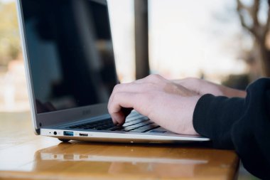 Vitiligo 'su olan, bilgisayarında tahta masada yazı yazan, kablosuz teknoloji konsepti fotokopi alanı olan tanınmamış genç adamın ellerini kapatın..