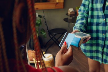 Kafede kredi kartıyla kablosuz elektromanyetik ödeme, yemek, ekonomi ve teknoloji için ödeme yapan tanınmayan bir kadının arka planı, kopyalama alanı.