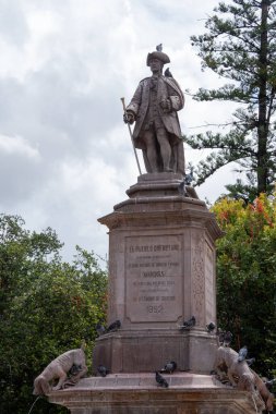 A statue of a man holding a sword and a plaque that says 