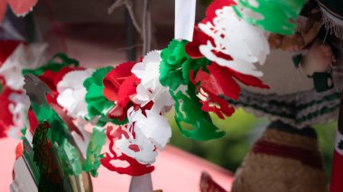 Duvarda kağıttan yapılmış renkli bir çelenk asılı. Çelenk kırmızı, beyaz renktedir. Queretaro şehrinin tarihi merkezi, Meksika 'nın Bağımsızlık Günü' nü, sömürge mimarisini, sokaklarını ve cephelerini kutlamak için dekorasyon ve gelenekler