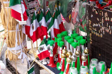 A table full of flags and other items with a Mexican theme. The flags are in various sizes. Historic center of Queretaro City, decorations and traditions to celebrate Mexico's Independence Day, colonial architecture, alleys and facades