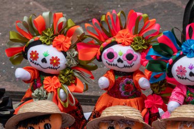 A group of dolls with colorful flowers and skulls on their faces. The dolls are arranged in a row. Historic center of Queretaro City, decorations and traditions to celebrate Mexico's Independence Day, colonial architecture, alleys and facades