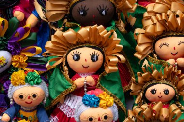 A collection of dolls with colorful clothing and accessories. The dolls are arranged in a row. Historic center of Queretaro City, decorations and traditions to celebrate Mexico's Independence Day, colonial architecture, alleys and facades