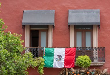 Yeşil yıldızlı kırmızı ve beyaz bir bayrak balkondan sarkıyor. Bayrak Meksika 'dan. Queretaro şehrinin tarihi merkezi, Meksika 'nın Bağımsızlık Günü' nü, sömürge mimarisini, sokaklarını ve cephelerini kutlamak için dekorasyon ve gelenekler