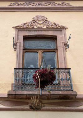 Metal bir sepetin içinde asılı duran bir pencere. Pencere bir balkonda. Queretaro şehrinin tarihi merkezi, Meksika 'nın Bağımsızlık Günü' nü, sömürge mimarisini, sokaklarını ve cephelerini kutlamak için dekorasyon ve gelenekler