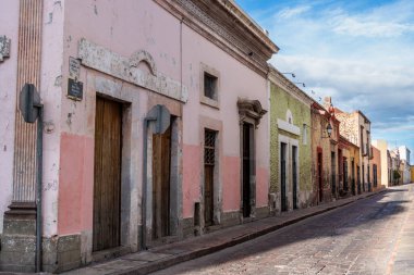 A row of colorful buildings with pink and green facades. The buildings are old. Historic center of Queretaro City, decorations and traditions to celebrate Mexico's Independence Day, colonial architecture, alleys and facades