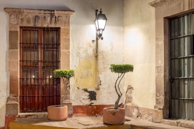 A small house with a door and a window. The door is open and the window is closed. Historic center of Queretaro, colonial architecture, decorations for the celebration of Mexico's Independence Day.