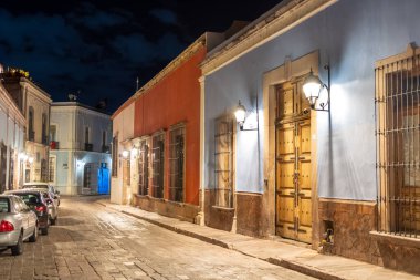 The street is lined with colorful buildings, with a blue building on the left and a red building on . Historic center of Queretaro, colonial architecture, decorations for the celebration of Mexico's Independence Day.