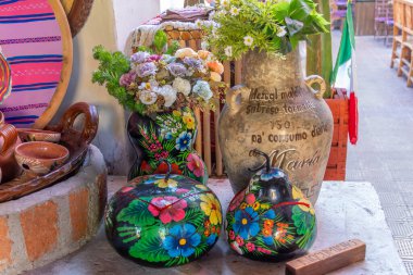 Three vases with colorful flowers are displayed on a table. Historic center of Queretaro, colonial architecture, decorations for the celebration of Mexico's Independence Day.