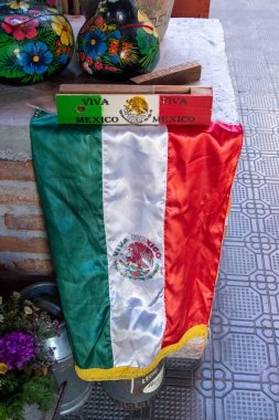 A Mexican flag is displayed on a wall. The flag is red, white, and green. Historic center of Queretaro, colonial architecture, decorations for the celebration of Mexico's Independence Day.