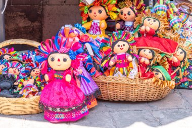 A collection of dolls with various outfits and accessories, including flowers and ribbons, are displ. Historic center of Queretaro, colonial architecture, decorations for the celebration of Mexico's Independence Day.