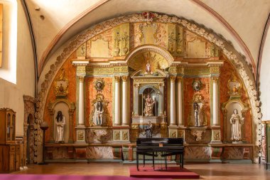 A large church with a piano in the middle. The piano is black and the room is decorated with statues. Historic center of Queretaro, colonial architecture, decorations for the celebration of Mexico's Independence Day.