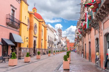 Arkasında beyaz bir bina olan küçük bir kasaba meydanı. Binanın üzerinde bir bayrak var. Queretaro 'nun tarihi merkezi, sömürge mimarisi, Meksika' nın Bağımsızlık Günü kutlamaları için dekorasyonlar.