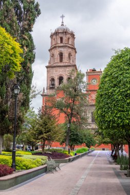 Arkasında beyaz bir bina olan küçük bir kasaba meydanı. Binanın üzerinde bir bayrak var. Queretaro 'nun tarihi merkezi, sömürge mimarisi, Meksika' nın Bağımsızlık Günü kutlamaları için dekorasyonlar.