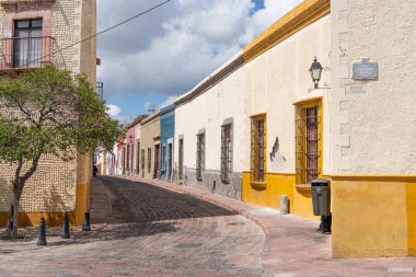 Arkasında beyaz bir bina olan küçük bir kasaba meydanı. Binanın üzerinde bir bayrak var. Queretaro 'nun tarihi merkezi, sömürge mimarisi, Meksika' nın Bağımsızlık Günü kutlamaları için dekorasyonlar.
