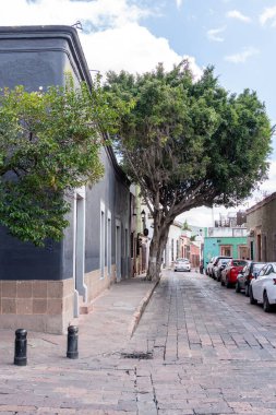 Arkasında beyaz bir bina olan küçük bir kasaba meydanı. Binanın üzerinde bir bayrak var. Queretaro 'nun tarihi merkezi, sömürge mimarisi, Meksika' nın Bağımsızlık Günü kutlamaları için dekorasyonlar.