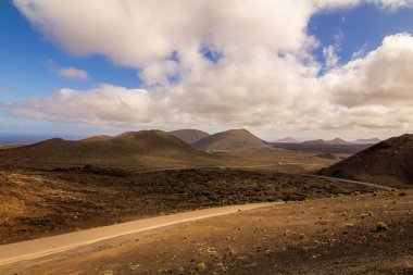 Çölün ortasında geniş ovalar, mavi gökyüzü ve bulutlar.