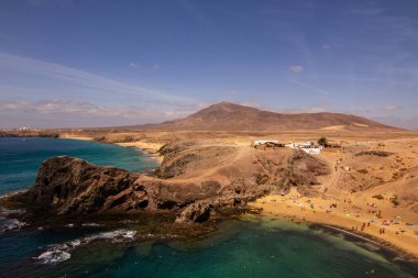 Lanzarote 'de kristal berrak deniz ile güzel sahil ve koy mavi gökyüzü ve arka plan dağlarıyla