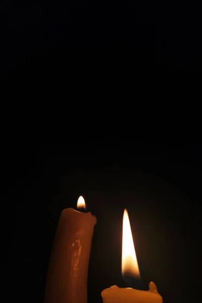 Candles are burning in the darkness. Two burning candles on black background close-up. Ukraine without electricity