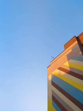 Corner of a new high-rise striped building against the background of the blue sky. House on the background of the blue sky. 