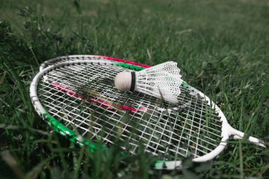 Dışarıdaki yeşil çimlerde badminton için badminton aletleri ve raketleri yakın çekim. Badminton ekipmanı. Açık hava eğlencesi ve spor konseptine ara veriyoruz..