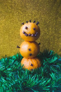 Noel için renkli arka planda kardan adam şeklinde üç turuncu mandalina. Noel ve Yeni Yıl kavramı. 