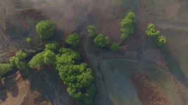 Aşağıya bakan yüksek irtifa uçuşu, sabah ışığı altında kısmen sislerle ve bulutlarla gizlenmiş bir arazide hareket ediyor.