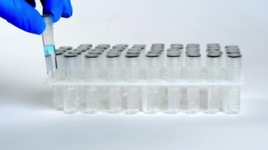 Mavi eldiven, laboratuarda durup test tüpünü tutabilmek için vakum tüpü yerleştirdi. Mikro küp