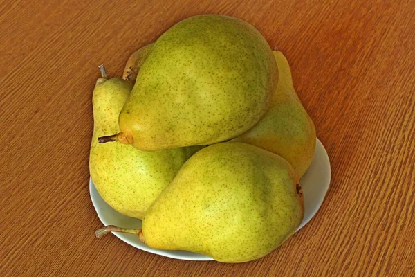 テーブルの表面に白いプレートに熟した甘い梨のまだ生活 軸方向のビュー — ストック写真