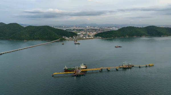 Aerial view of oil tanker ship loading in port, Oil tanker ship under cargo operations on typical shore station with clearly visible mechanical loading arms and pipeline refinery zone background,