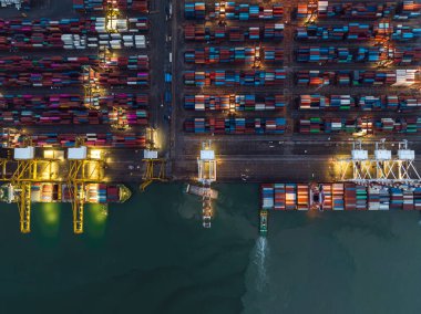 hava üst görünümü uluslararası nakliye portu yükü ve konteynırları vinçle nakliye gemilerine yükleme ve ihracat ürünlerini müşterilere ve tüketicilere gece olay yerinde ışıklandırma üzerinden ihraç etmek için römork